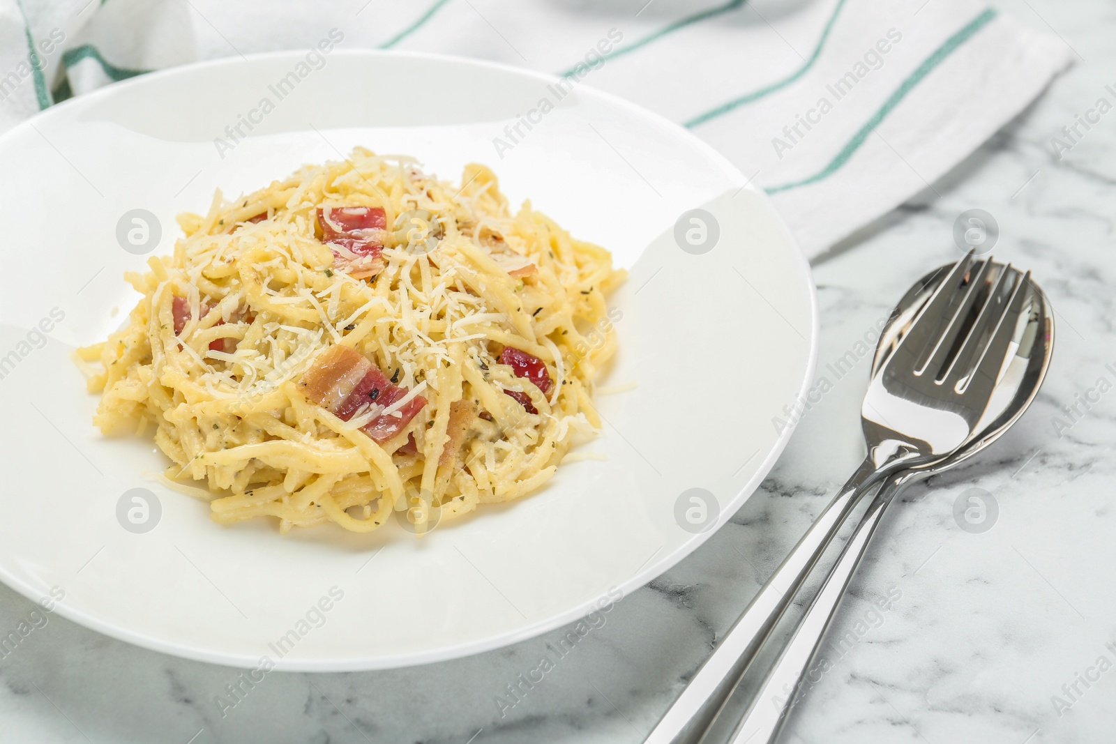 Photo of Delicious pasta Carbonara with bacon served on white marble table, closeup