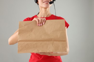 Photo of Fast-food worker with paper bag on gray background, closeup