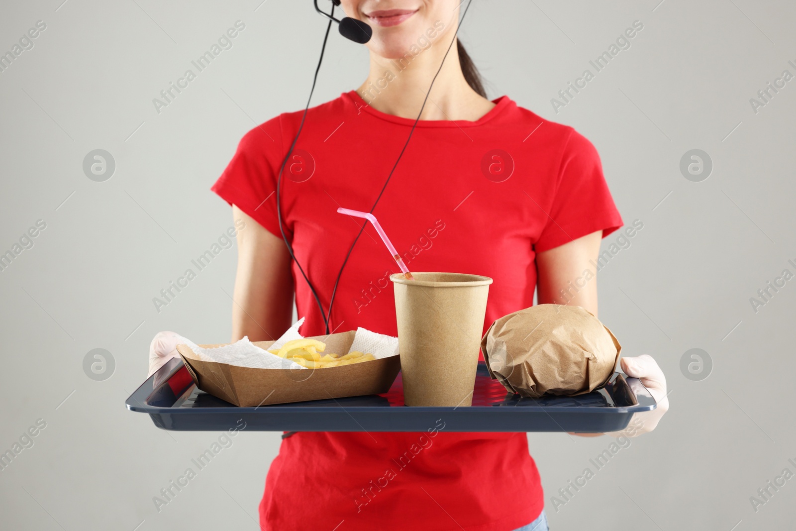 Photo of Fast-food worker holding tray with order on gray background, closeup