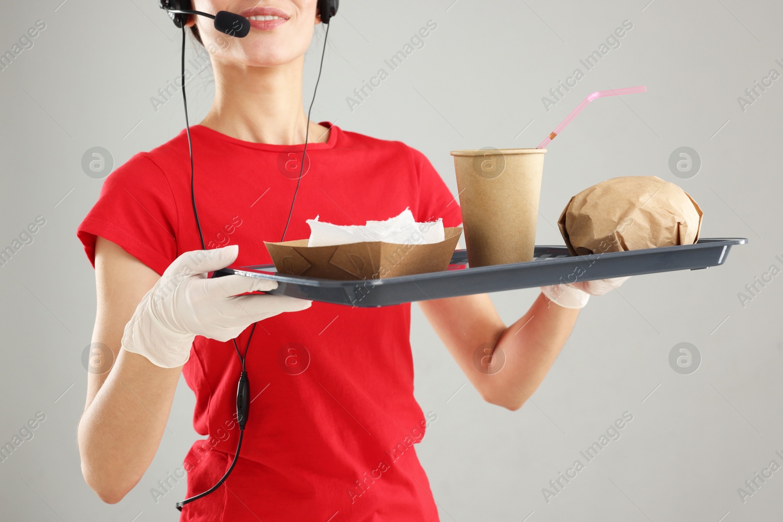 Photo of Fast-food worker holding tray with order on gray background, closeup