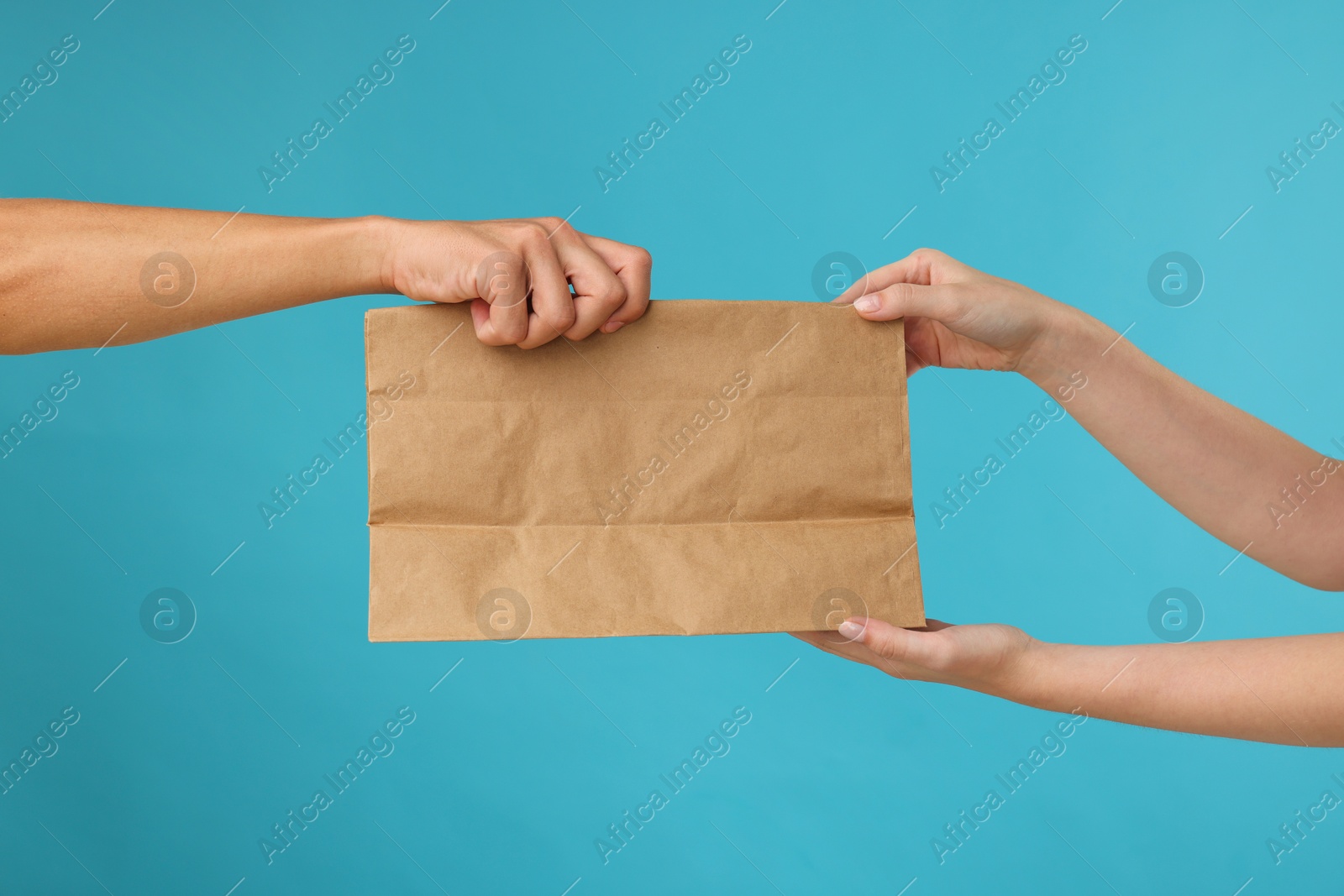 Photo of Fast-food worker giving customer's order on light blue background, closeup