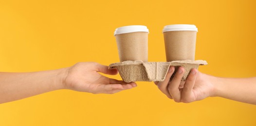 Photo of Fast-food worker giving customer's order on orange background, closeup