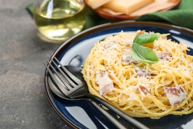 Photo of Plate with delicious pasta Carbonara and cutlery on grey textured table, closeup. Space for text