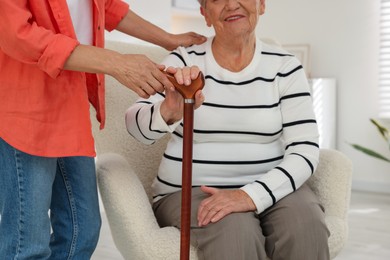 Photo of Caregiver supporting senior woman in living room at home, closeup