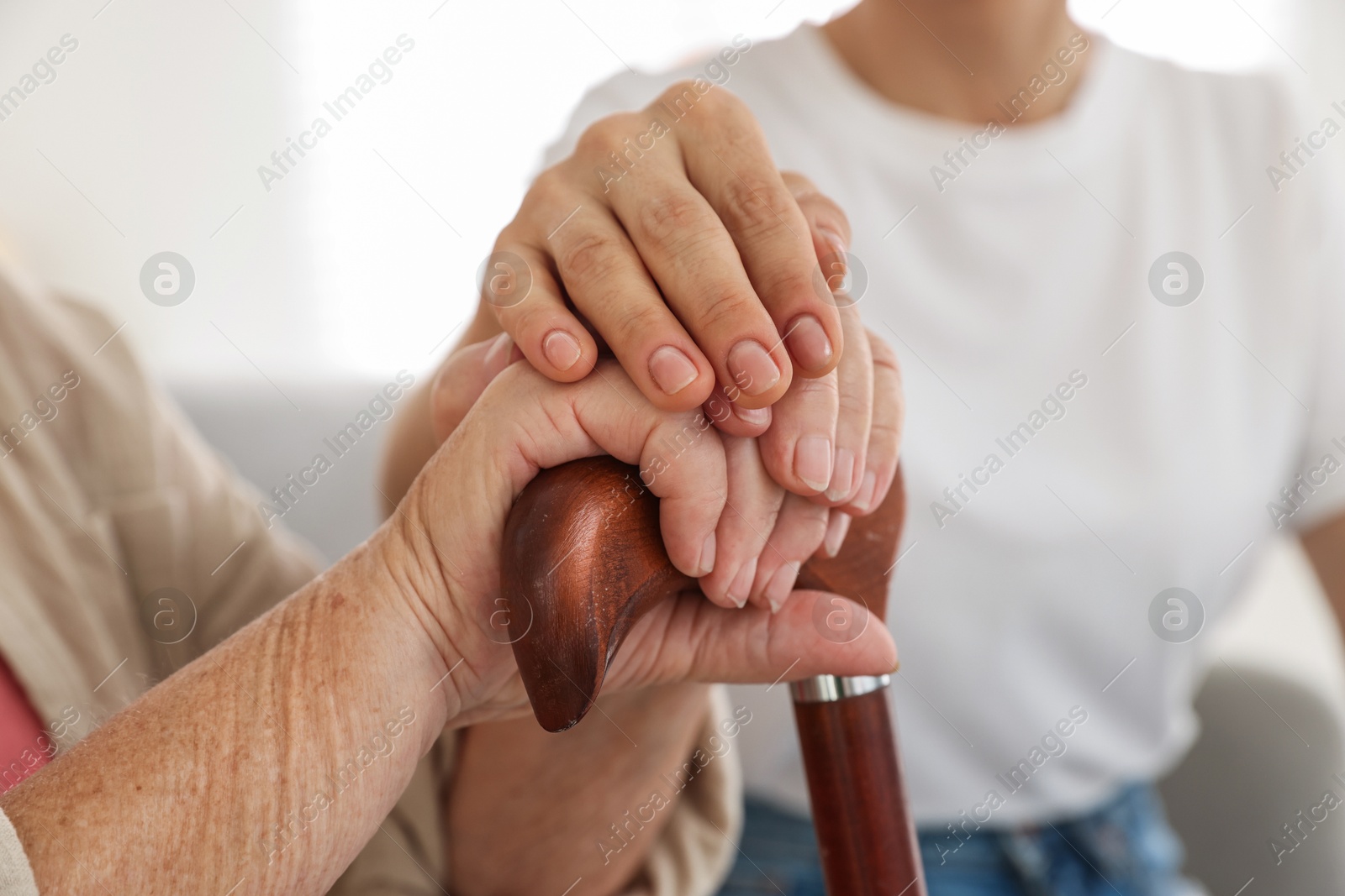 Photo of Caregiver supporting senior woman at home, closeup