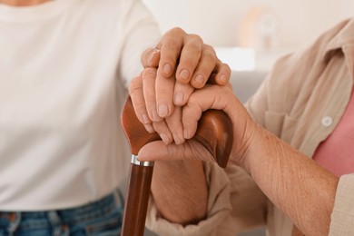 Caregiver supporting senior woman at home, closeup