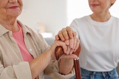 Caregiver supporting senior woman at home, closeup