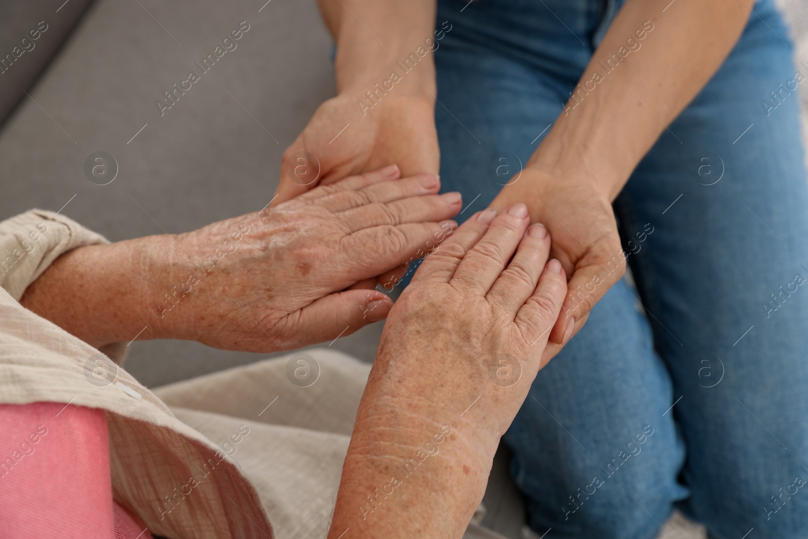 Photo of Caregiver supporting senior woman at home, closeup