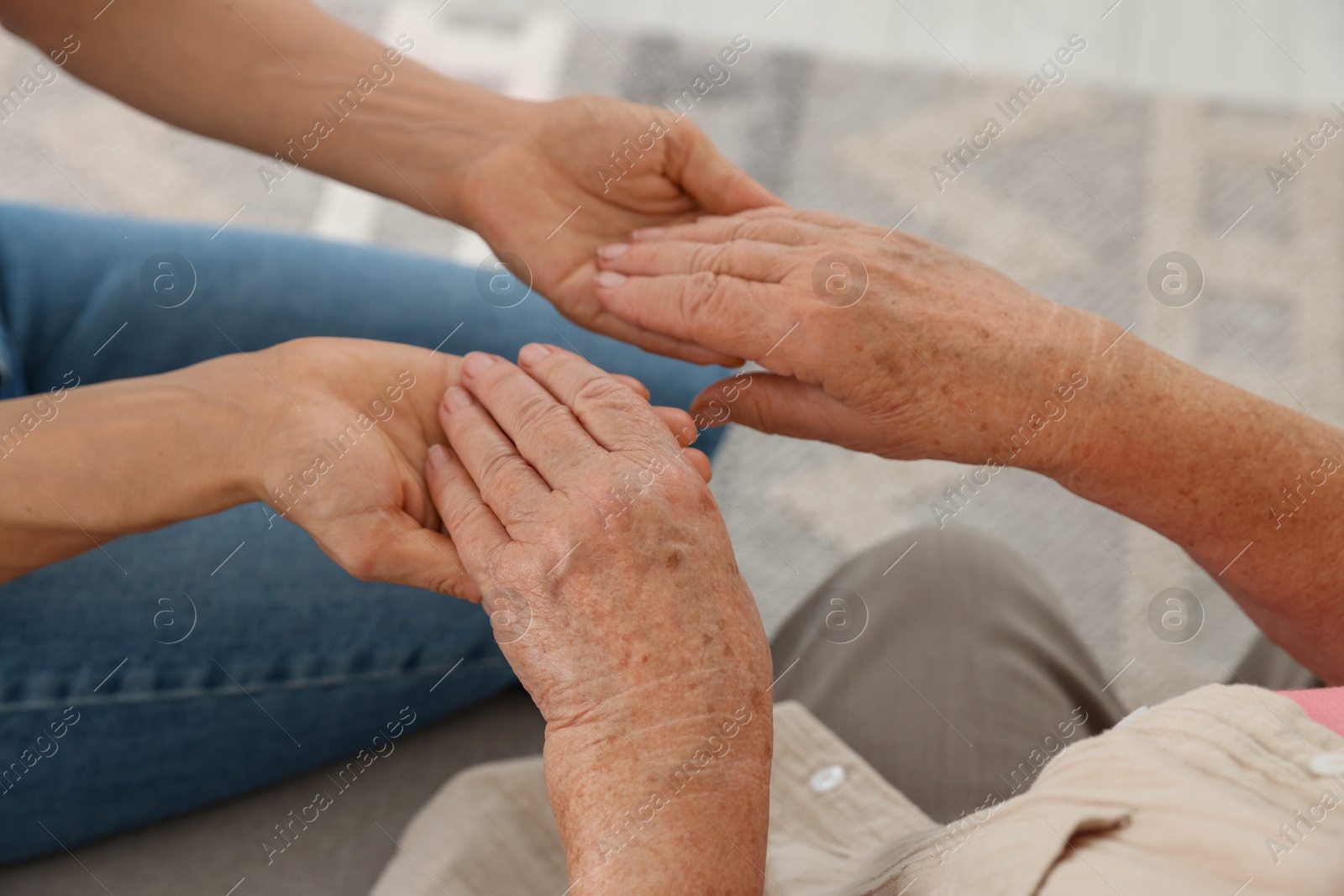 Photo of Caregiver supporting senior woman at home, closeup