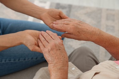 Photo of Caregiver supporting senior woman at home, closeup