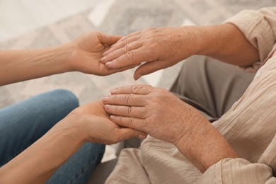 Photo of Caregiver supporting senior woman at home, closeup