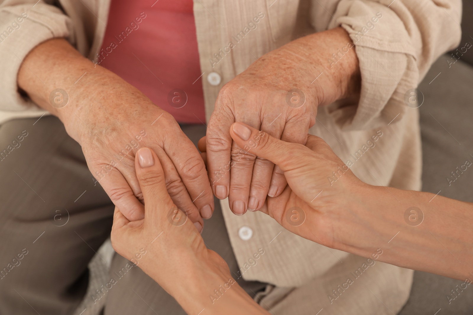 Photo of Caregiver supporting senior woman at home, closeup