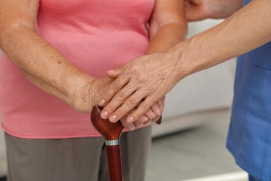 Photo of Healthcare worker supporting senior patient indoors, closeup