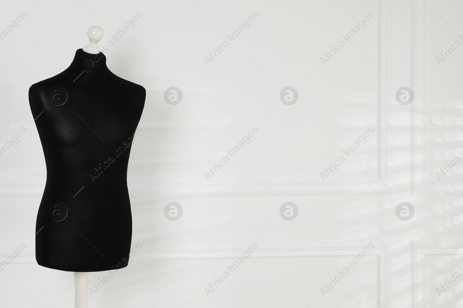 Photo of One black female mannequin near light wall. Space for text