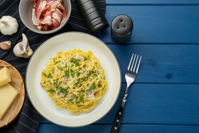 Photo of Delicious pasta Carbonara served on blue wooden table, flat lay