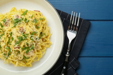 Photo of Delicious pasta Carbonara served on blue wooden table, flat lay