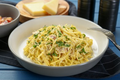 Photo of Delicious pasta Carbonara served on blue wooden table, closeup