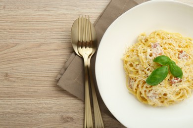 Photo of Delicious pasta Carbonara served on wooden table, flat lay