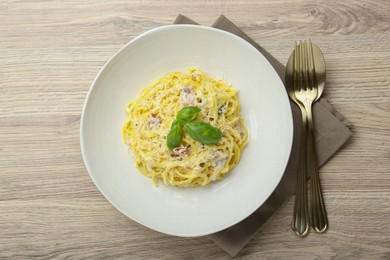 Photo of Delicious pasta Carbonara served on wooden table, flat lay