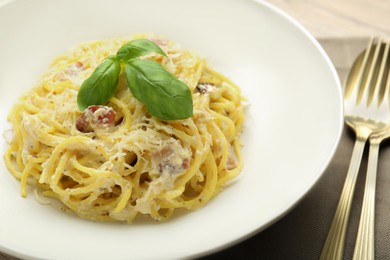 Photo of Delicious pasta Carbonara with basil on table, closeup