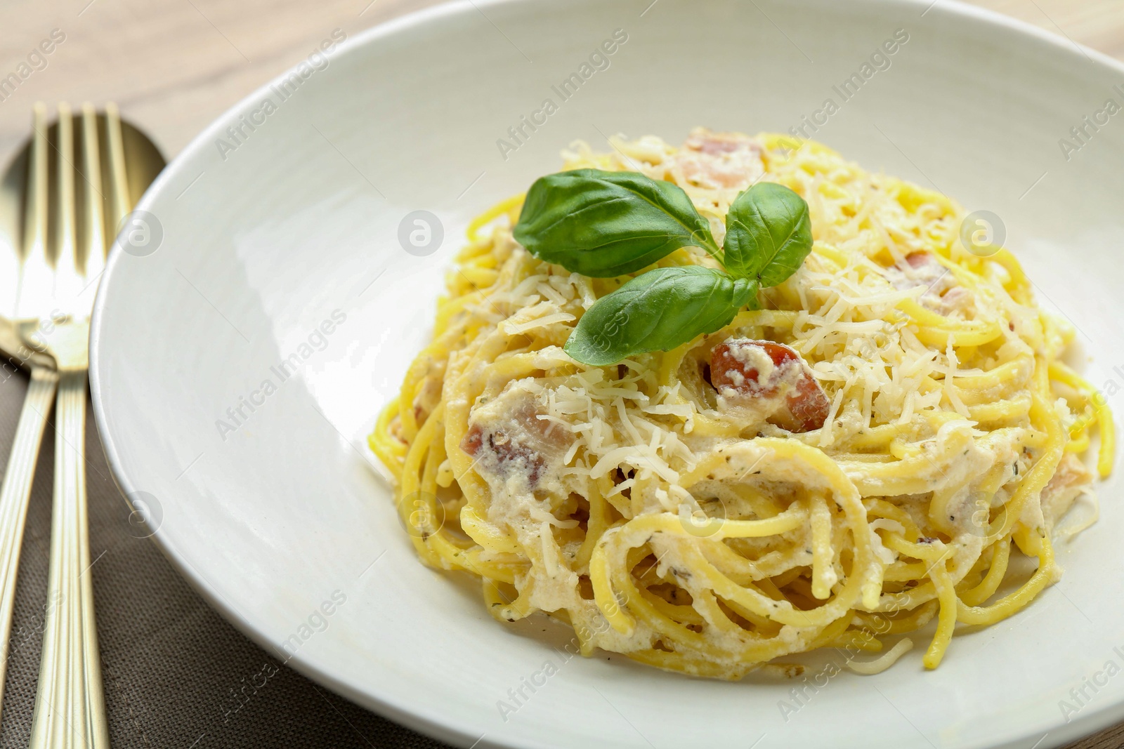 Photo of Delicious pasta Carbonara with basil on table, closeup