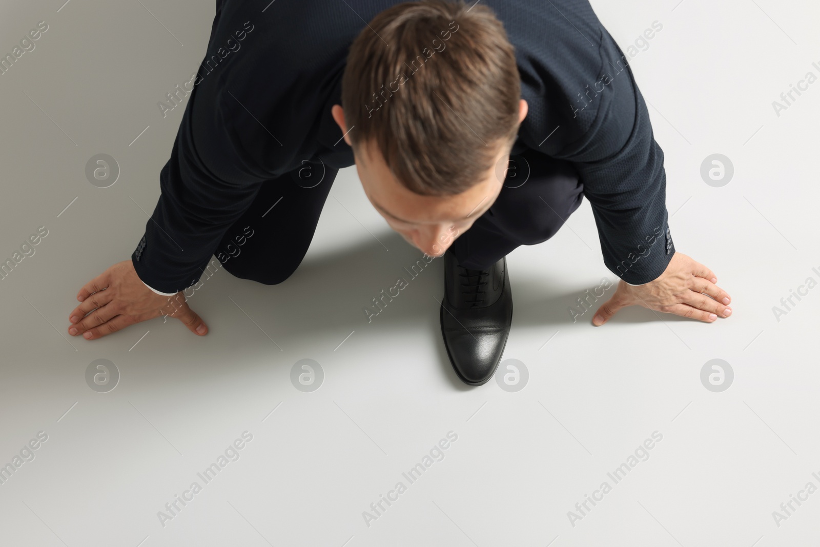 Photo of Businessman in starting position for run on light grey background, above view