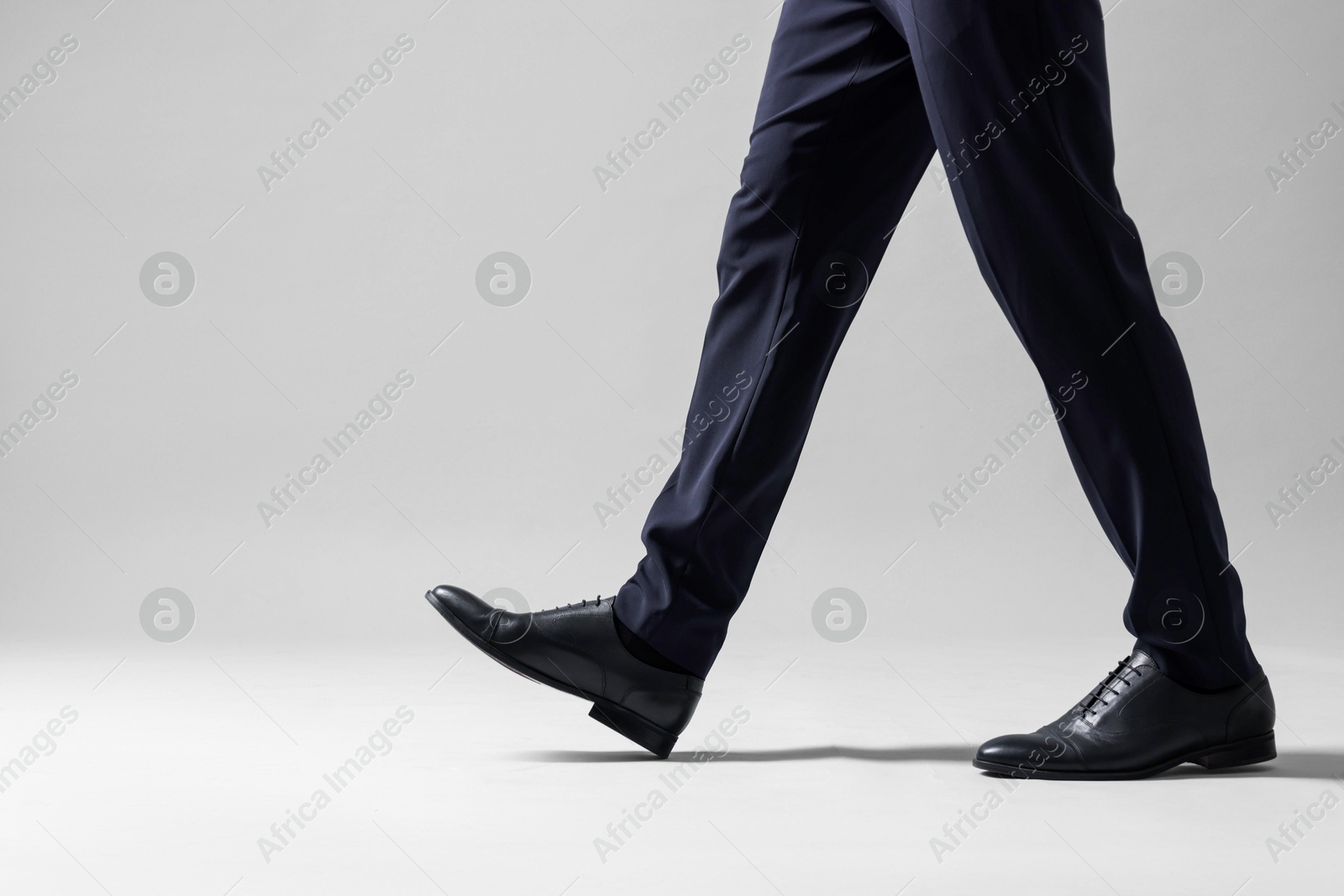 Photo of Businessman walking on light grey background, closeup