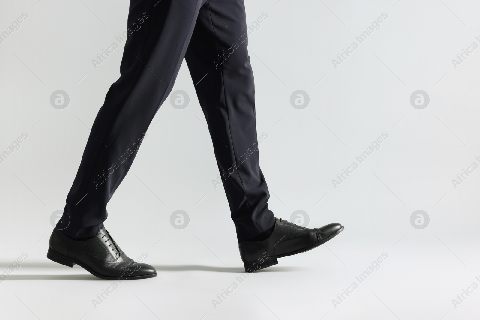 Photo of Businessman walking on light grey background, closeup