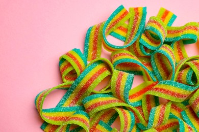 Photo of Tasty rainbow sour belts on pink background, top view