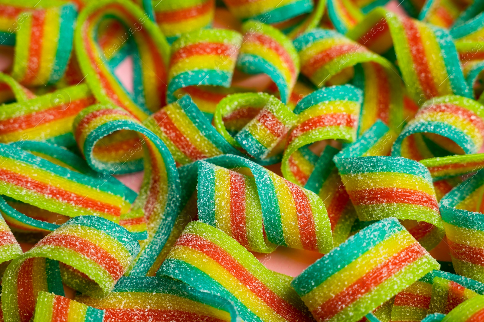 Photo of Tasty rainbow sour belts on pink background, closeup