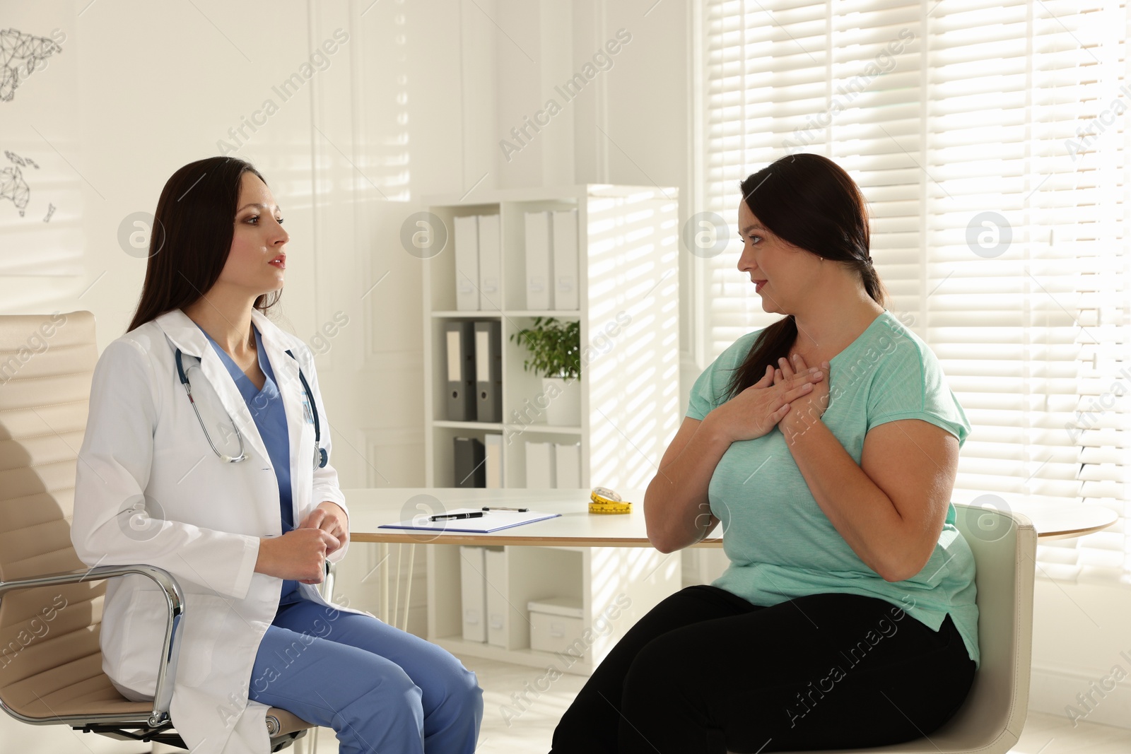 Photo of Nutritionist giving recommendations to overweight woman in hospital