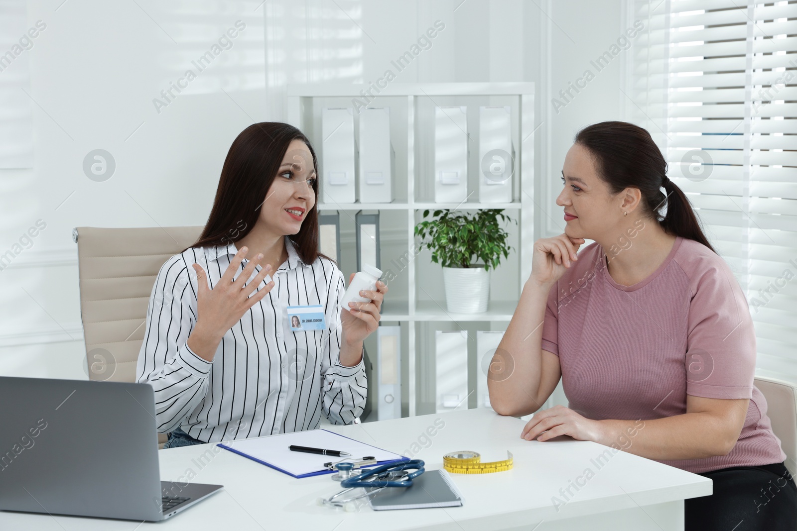 Photo of Overweight woman having consultation with nutritionist at desk in clinic