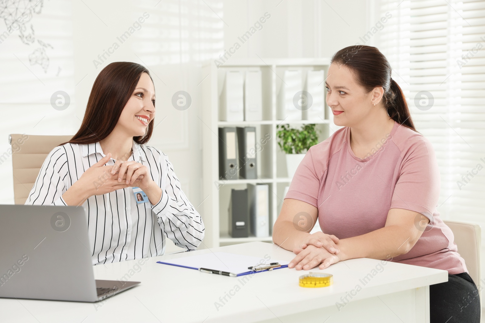 Photo of Overweight woman having consultation with nutritionist at desk in clinic