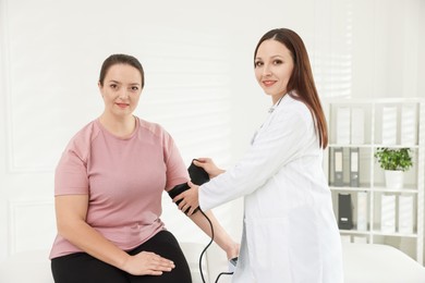 Photo of Nutritionist measuring overweight woman's blood pressure in hospital