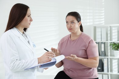 Photo of Nutritionist with clipboard giving recommendations to overweight woman in hospital