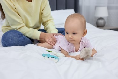 Photo of Mother and her cute little baby with rattles on bed indoors, closeup