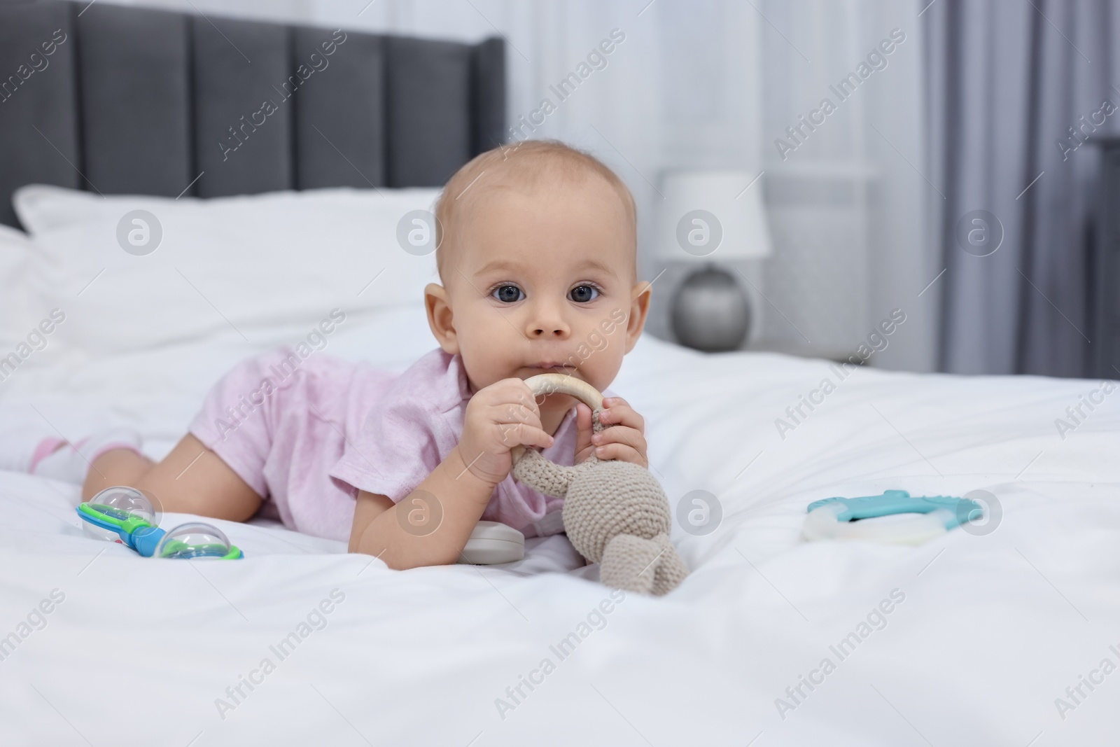 Photo of Cute little baby with rattles on bed indoors, space for text