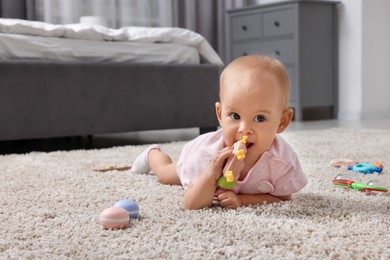 Photo of Cute little baby with rattles on floor indoors