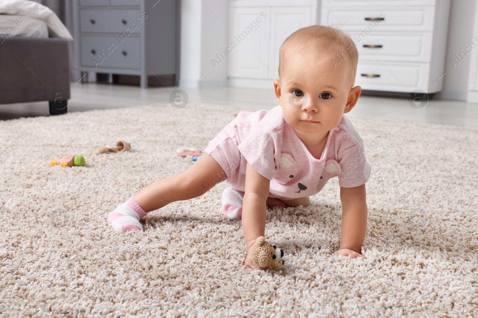 Photo of Cute little baby with rattles on floor indoors