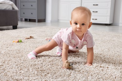 Photo of Cute little baby with rattles on floor indoors