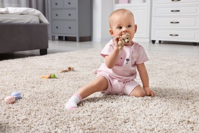 Photo of Cute little baby with rattles on floor indoors