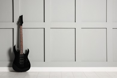 Photo of One modern electric guitar near grey wall. Space for text