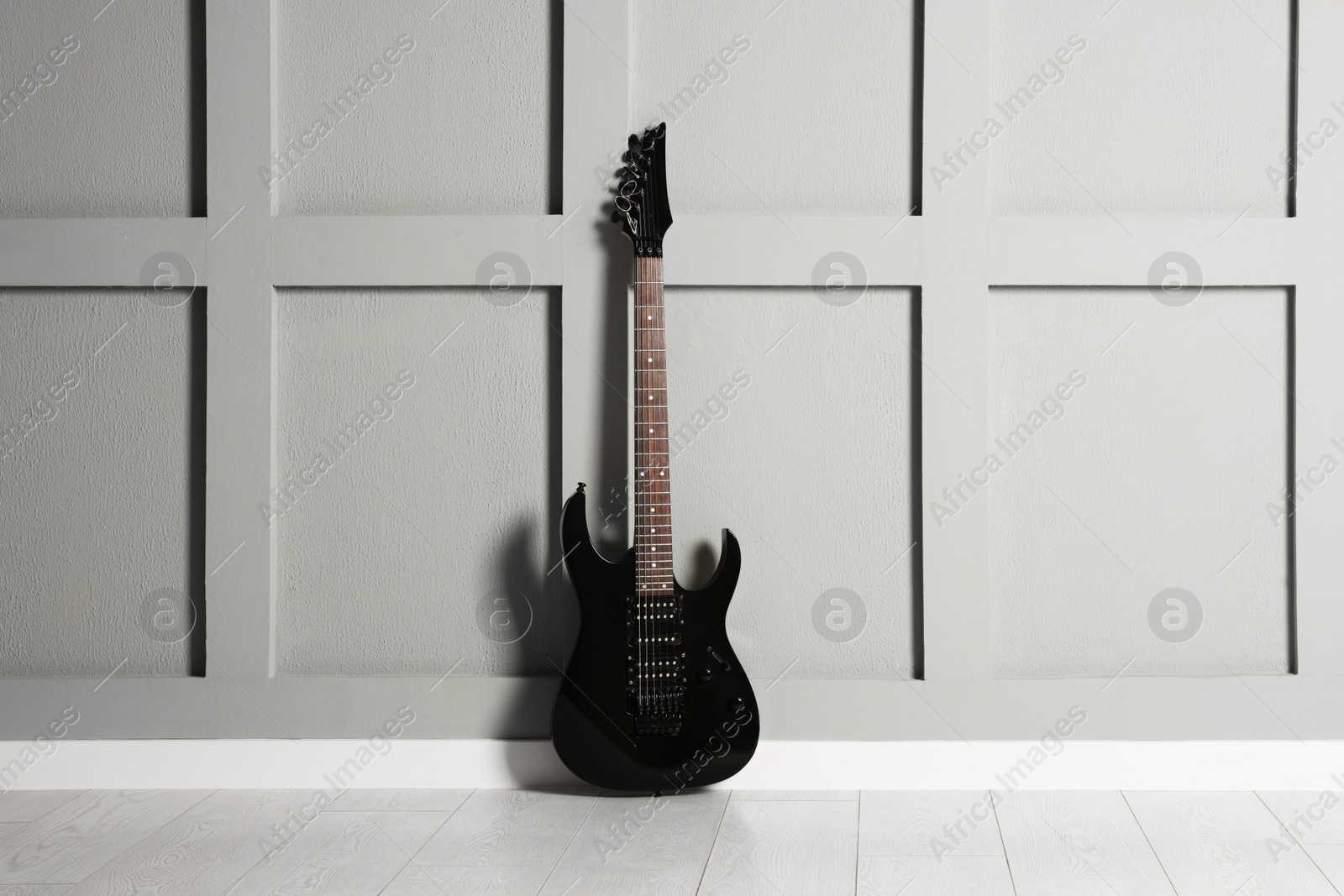 Photo of One modern electric guitar near grey wall