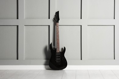 One modern electric guitar near grey wall