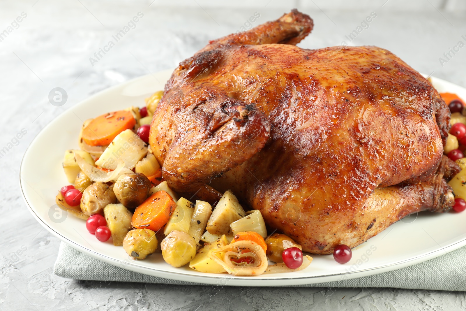 Photo of Delicious baked turkey, vegetables and cranberries on gray textured table, closeup