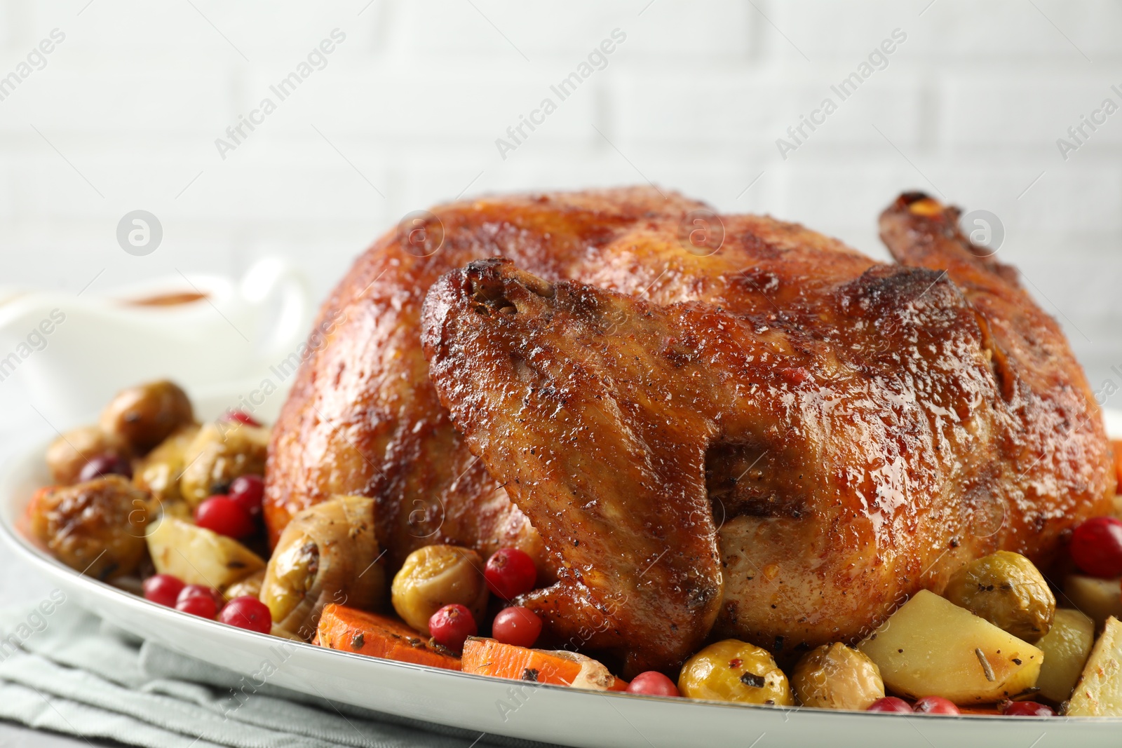 Photo of Delicious baked turkey, vegetables and cranberries on table against white background, closeup