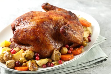 Photo of Delicious baked turkey, vegetables and cranberries on gray textured table, closeup