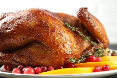 Photo of Delicious baked turkey, orange slices, cranberries and thyme on table, closeup