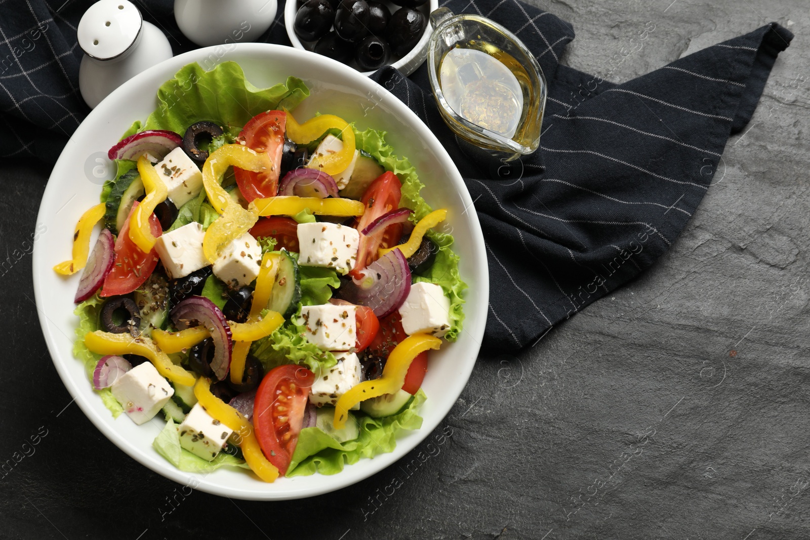 Photo of Delicious fresh Greek salad served on black table, flat lay. Space for text