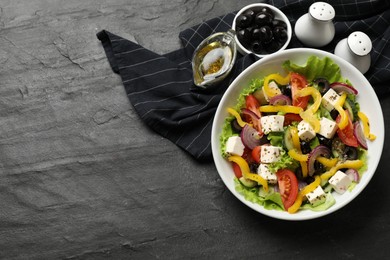 Photo of Delicious fresh Greek salad served on black table, flat lay. Space for text